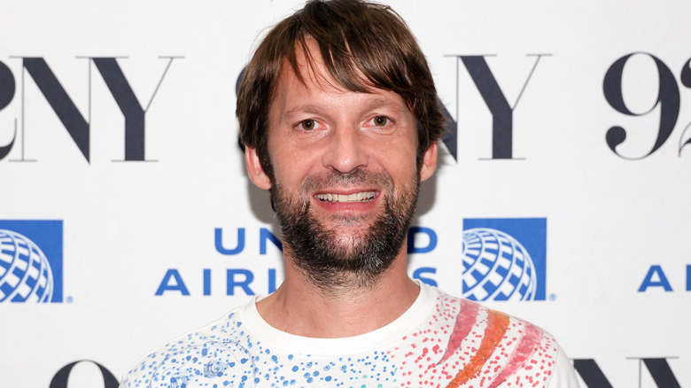 Restaurateur and chef René Redzepi smiling for cameras at publicity event.