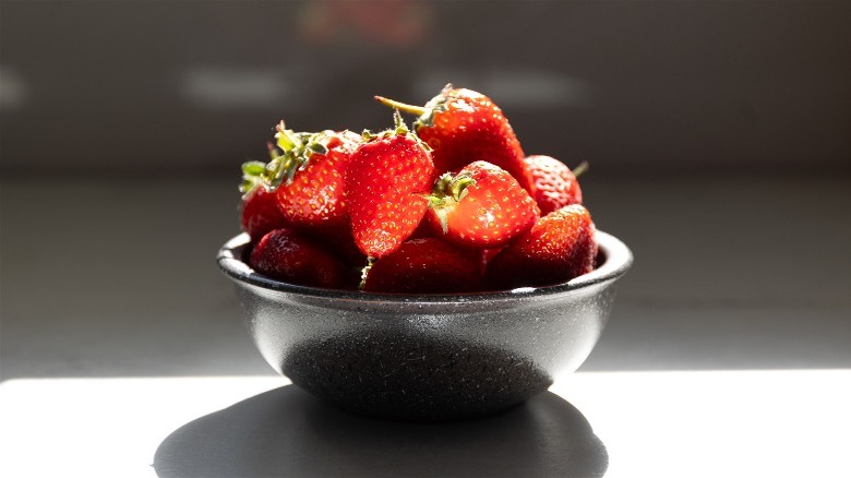 Strawberries in a black bowl on a counter