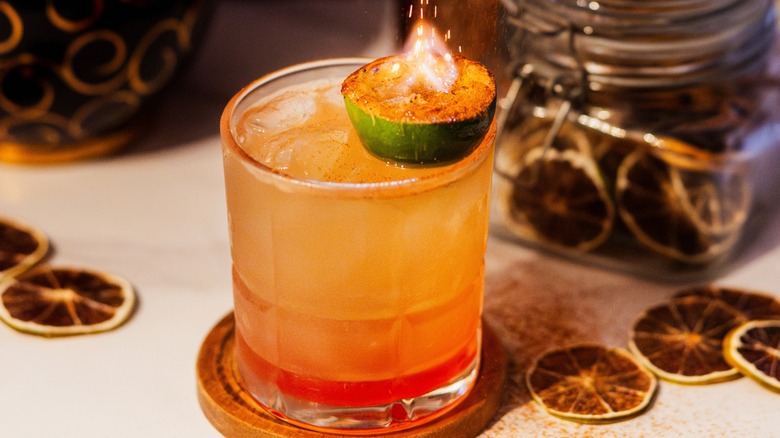 Half of lime on fire on top of cocktail