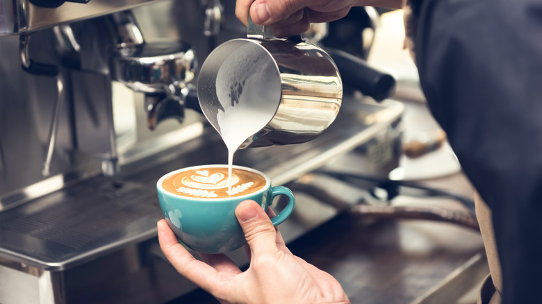 Barista pouring milk into an espresso mug