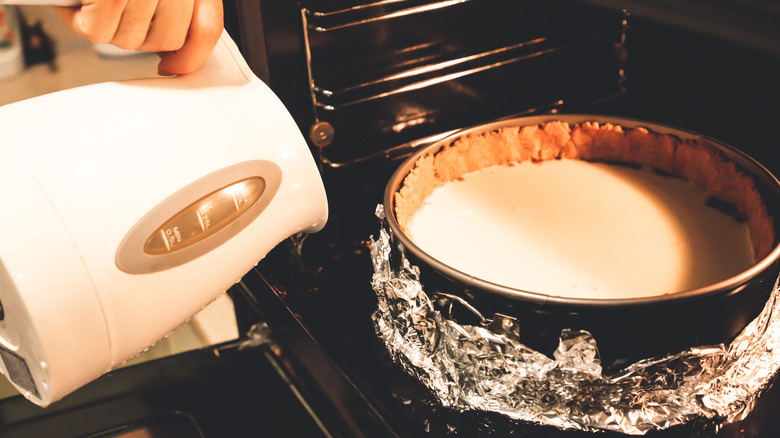 water being poured into a water bath to bake cheesecake