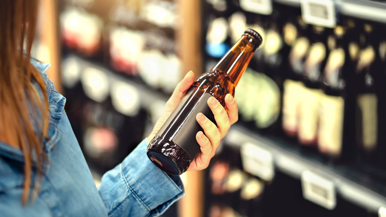 Grocery shopper holding beer bottle