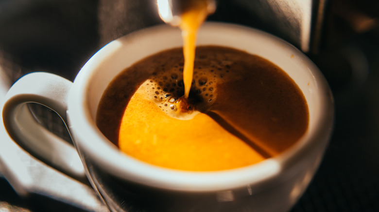 Cup with espresso pouring in