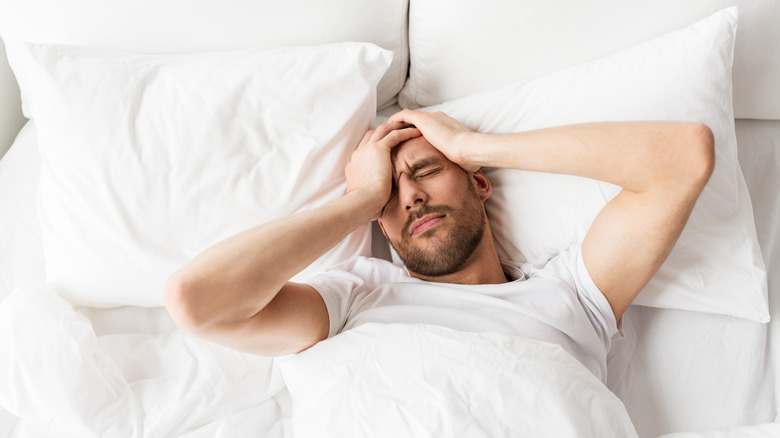 A man in a bed with a hangover headache