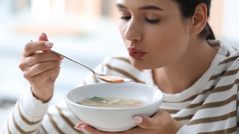 Woman blowing on bowl of hot soup