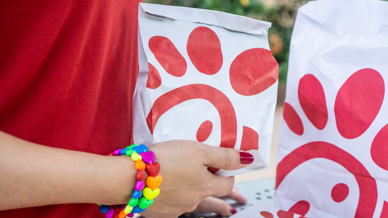 Arm with heart bracelets holding Chick-fil-A bag