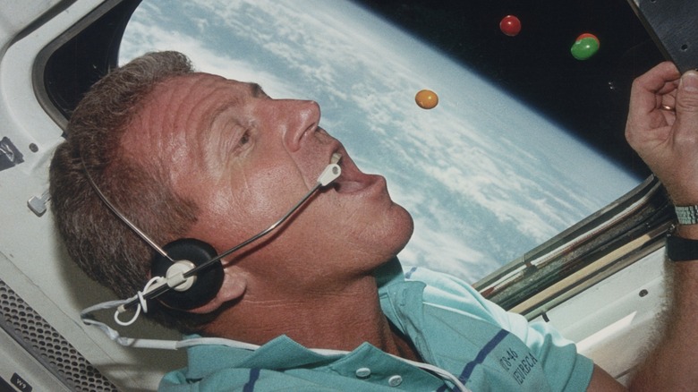 Astronaut Loren Shriver eats M&M's in space with Earth in background