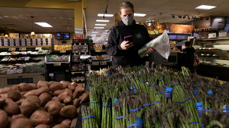An Instacart shopper holding asparagus in the supermarket