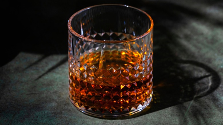 A glass of Scotch whisky against a dark gray backdrop.