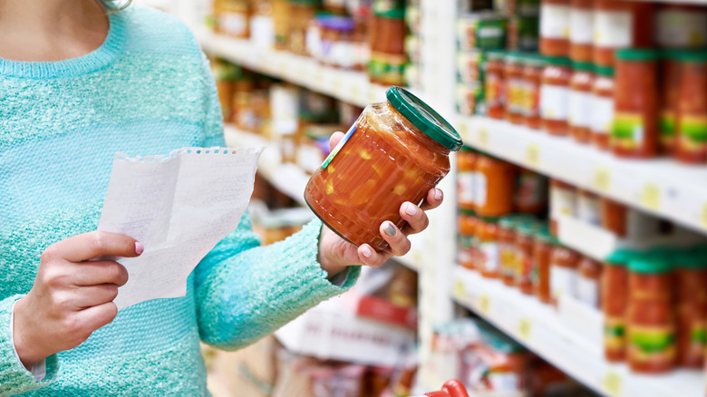 Person shopping for jarred sauce in grocery store.