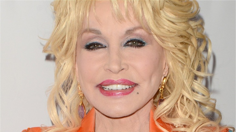 Closeup of Dolly Parton in gold earrings and orange top