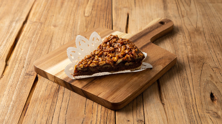 Slice of walnut pie on cutting board