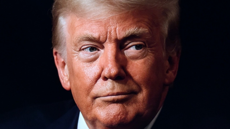 Donald Trump smirking against black background