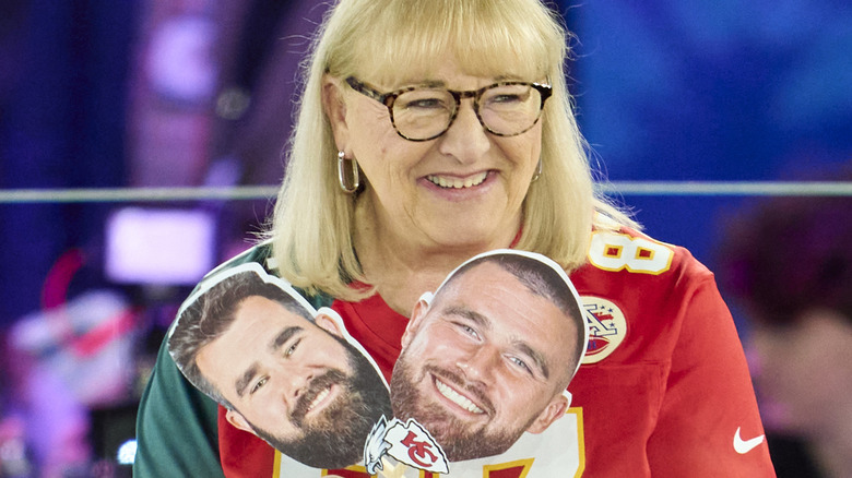 Donna Kelce holding signs of Travis and Jason Kelce's heads