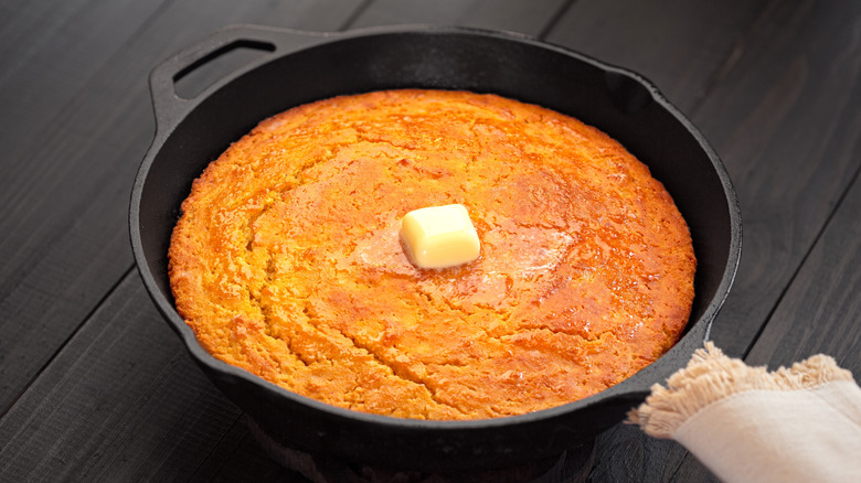 Cornbread in a cast iron skillet with a dollop of butter