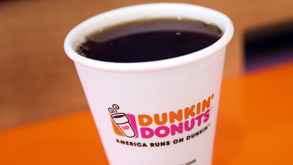Paper cup of coffee imprinted with Dunkin's logo