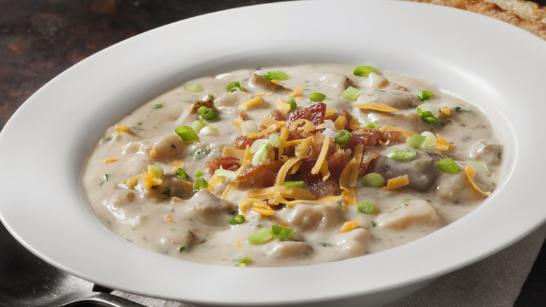 Bowl of potato soup topped with bacon, chives, and cheese