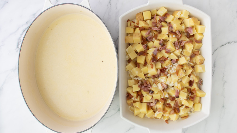 ham and potatoes in a white pan next to a pot of white liquid