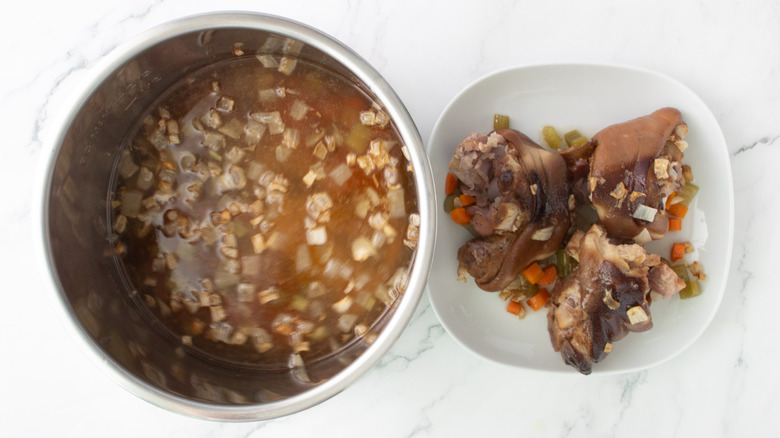 ham hocks next to vegetables in a metal pot