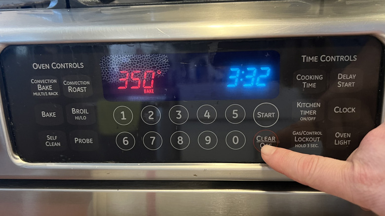 hand touching oven temperature gauge