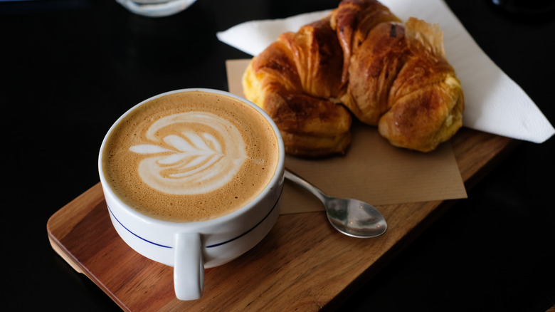 Latte with croissant on table