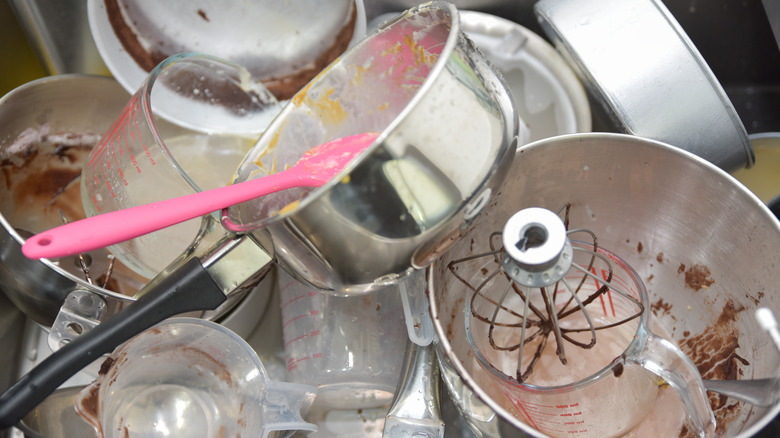 A pile of dirty dishes in the sink at a bakery