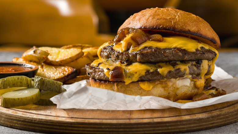 A double cheeseburger on a wooden platter