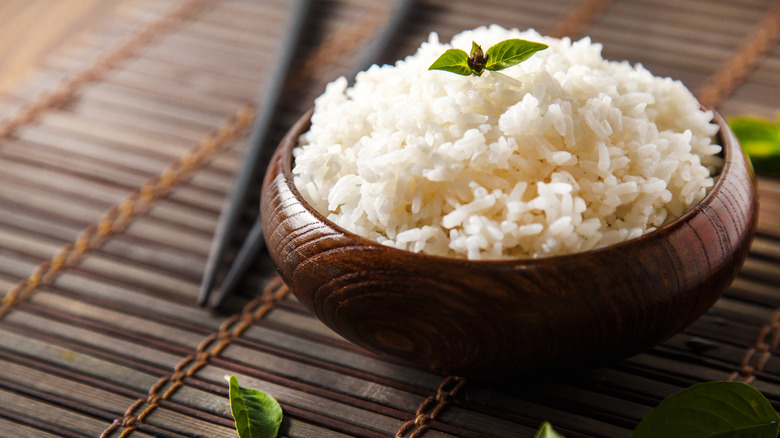 bowl of white rice with chopsticks in background