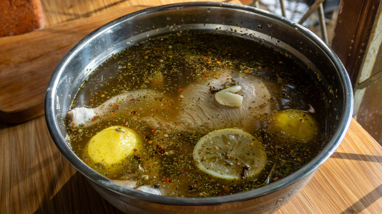 Chicken brining in bowl with lemons and spices