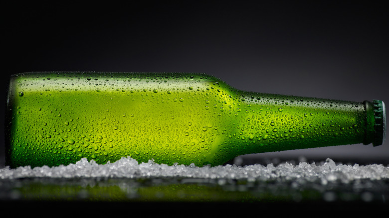 Beer lying on its side on a black surface with condensation covering the bottle