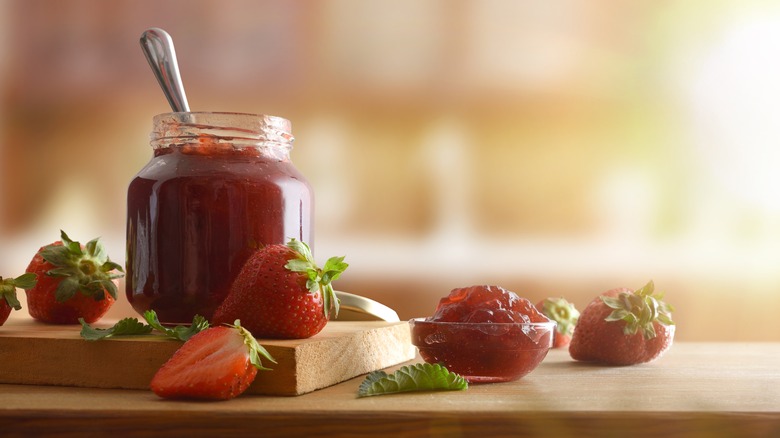 jar of strawberry preserves with fresh strawberries nearby