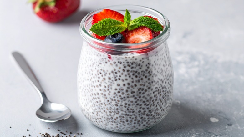 jar of chia seed pudding with strawberries, a blueberry and a sprig of mint on top