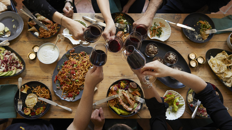Group of people clinking wine glasses over a meal