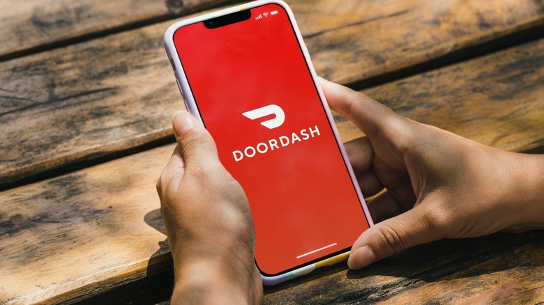 Two hands holding a phone that's displaying the DoorDash app