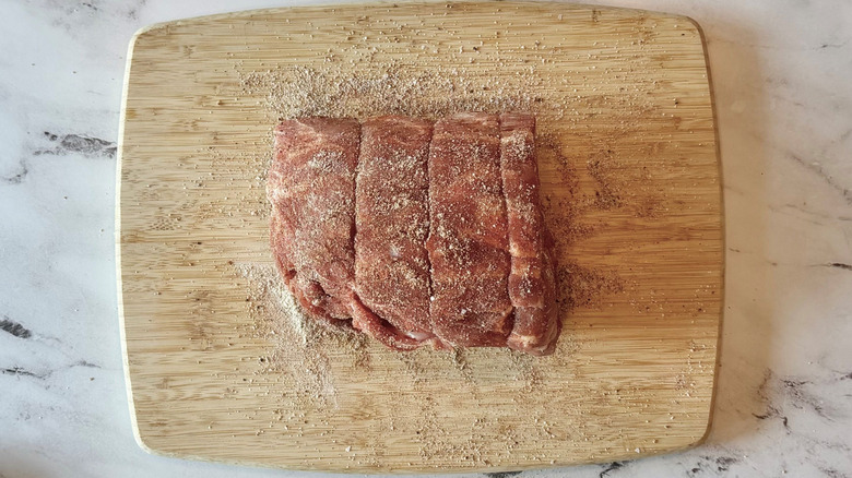 Seasoned, uncooked pork butt on cutting board