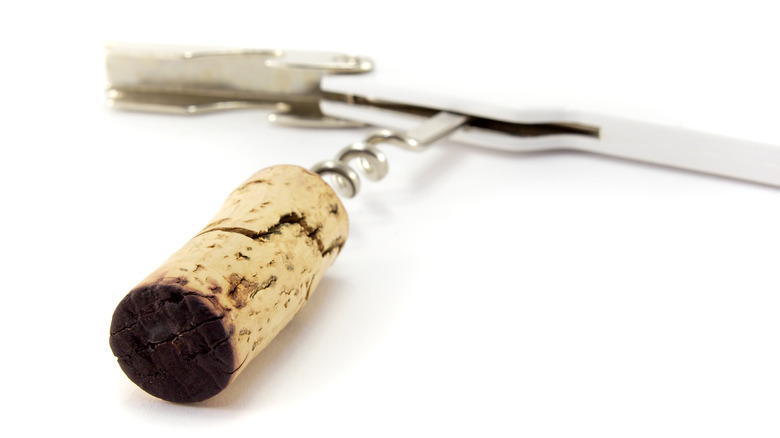 Cracked wine cork with dark bottom attached to corkscrew