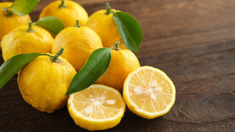 close up of yuzu fruit with leaves on wooden background