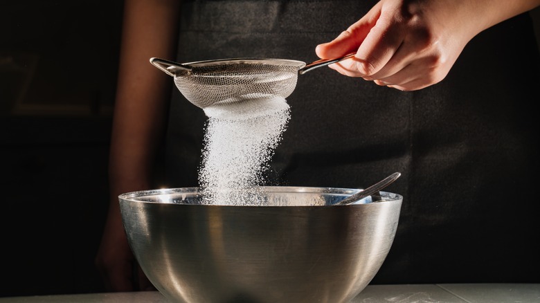 sifting flour into a metal bowl