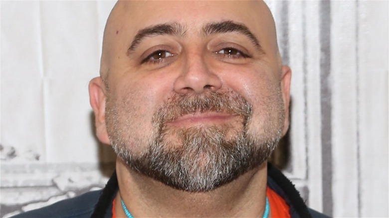 A close-up of Duff Goldman wearing a blue necklace and black jacket