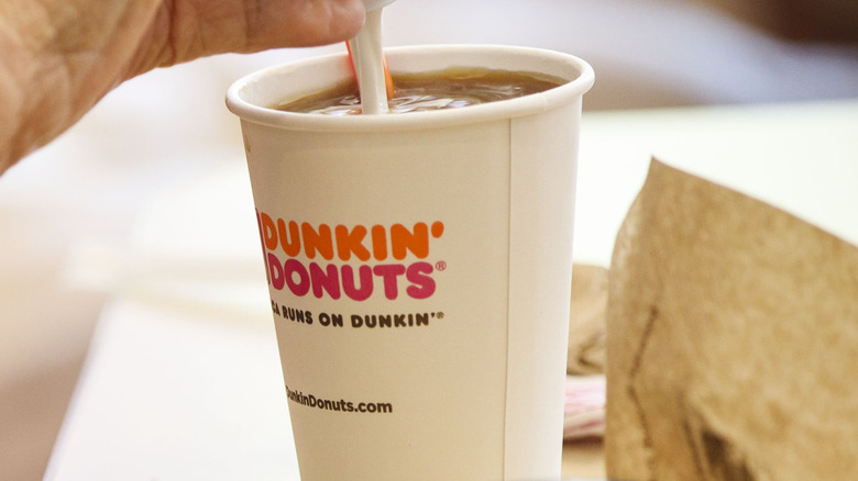 person pouring creamer into coffee