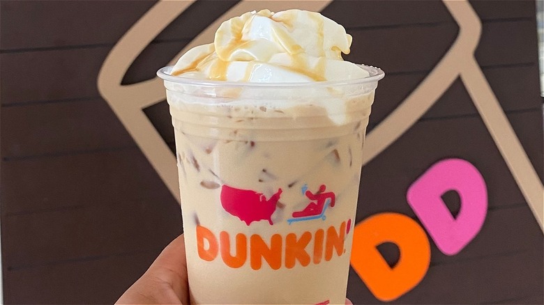 a person holding a dunkin coffee