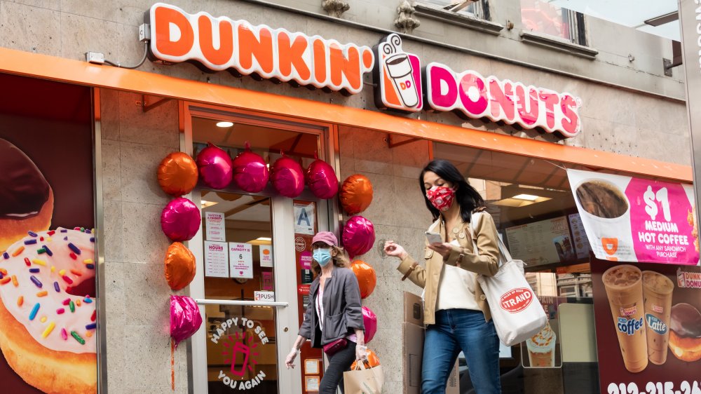 woman in front of a Dunkin' Donuts store