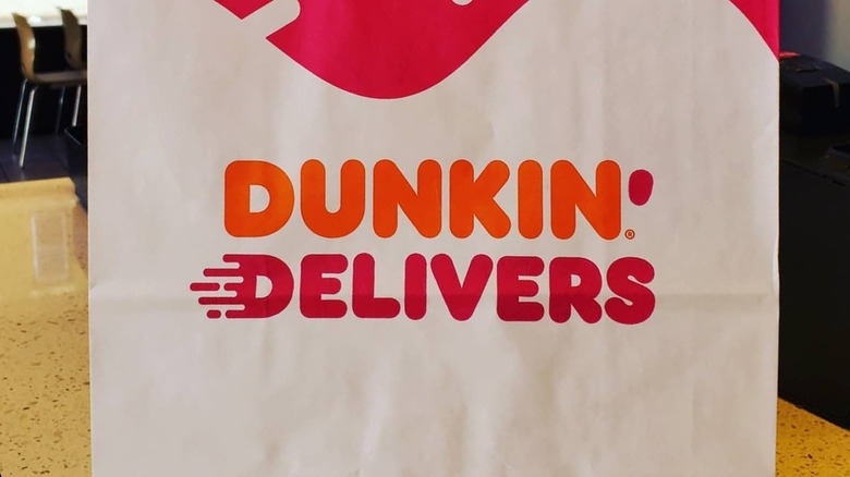 A to-go back from Dunkin' with the words "Dunkin' Delivers" on it