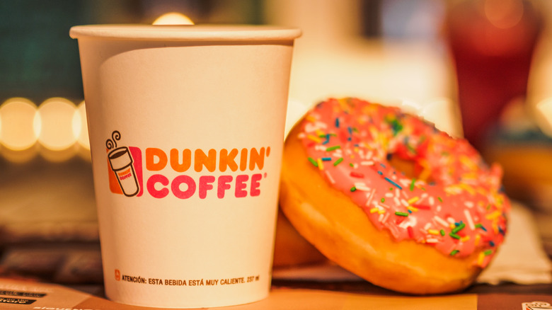 Dunkin' to-go cup and pink doughnut with sprinkles