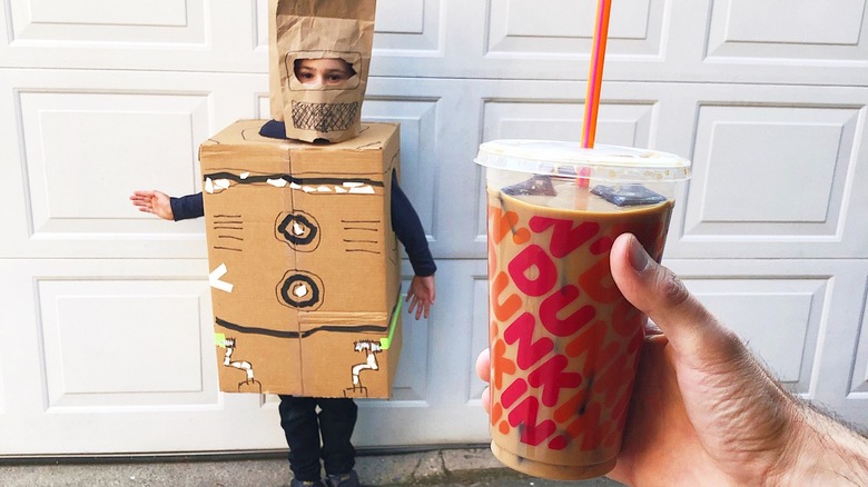 hand holds Dunkin' Donuts with costumed child