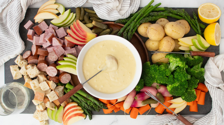 Cheese fondue with various vegetable, meat, and fruit dippers