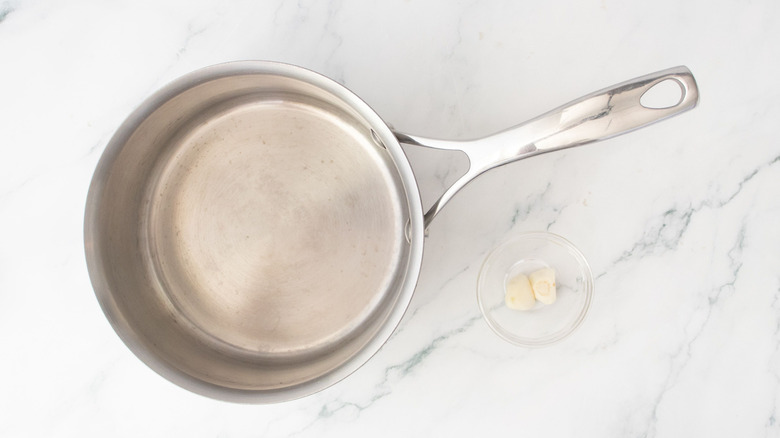 Saucepan next to small bowl of garlic