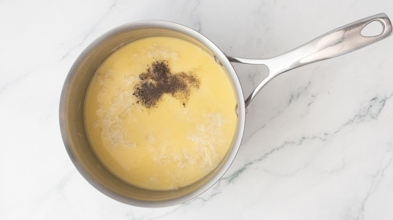 Melted cheese and black pepper in saucepan