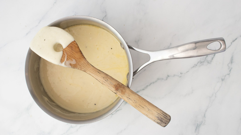 Cheese fondue in saucepan with wooden spoon on top