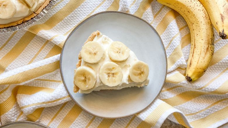 slice of banana cream pie sits beside bananas